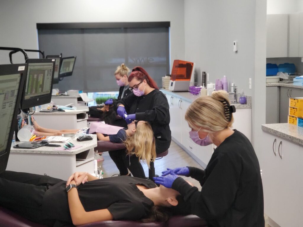 Orthodontic technicians performing teeth cleaning or preparatory work in a modern orthodontics office.