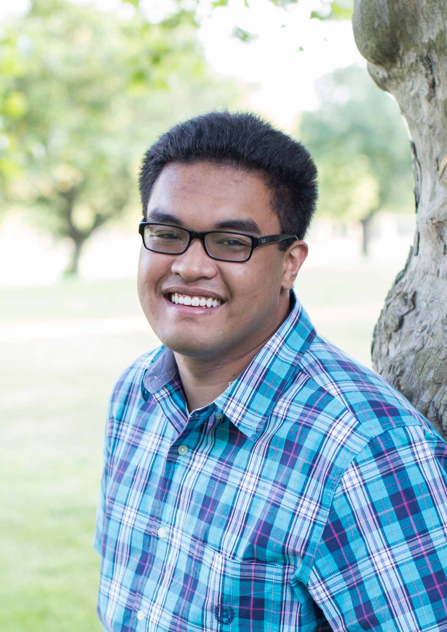 Hispanic male wearing glasses and smiling warmly.