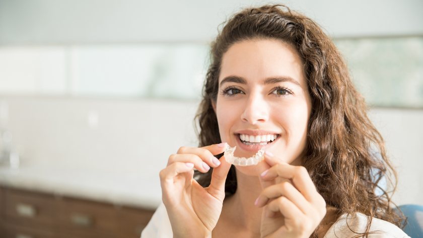 A woman getting ready to insert her Invisalign aligners.