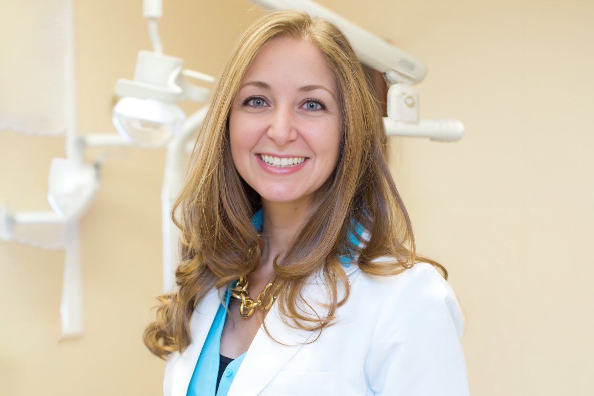 Dr. Tara Gostovich smiling warmly in her dental office.