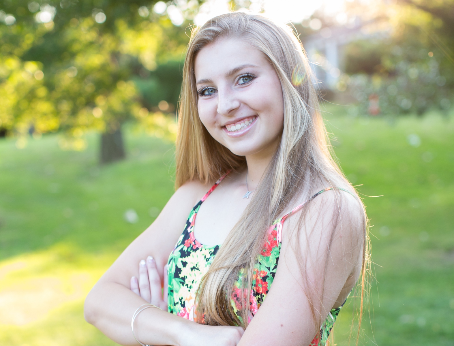 A young woman in a floral top smiling brightly.