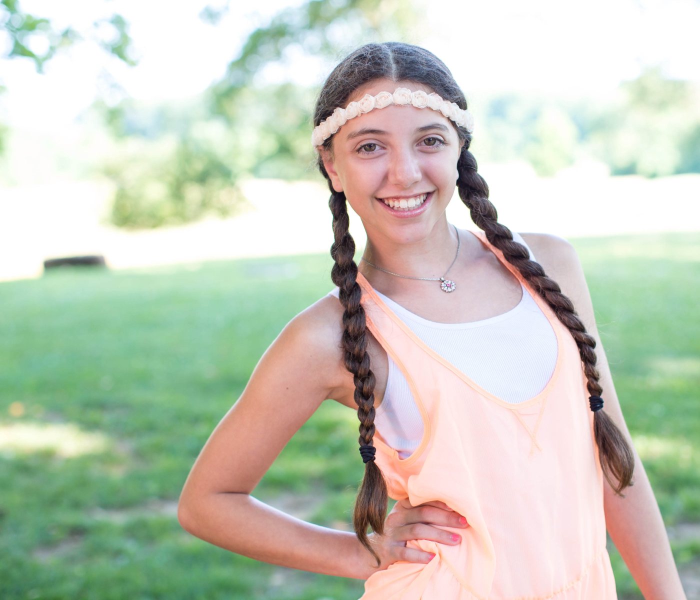 A ponytailed girl smiling and showing off her Invisalign aligners.