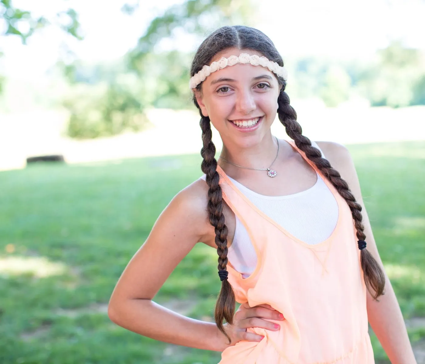 Smiling girl with braided hair outdoors on a sunny day, the kind of confident smile families want from an orthodontist in Colts Neck, NJ