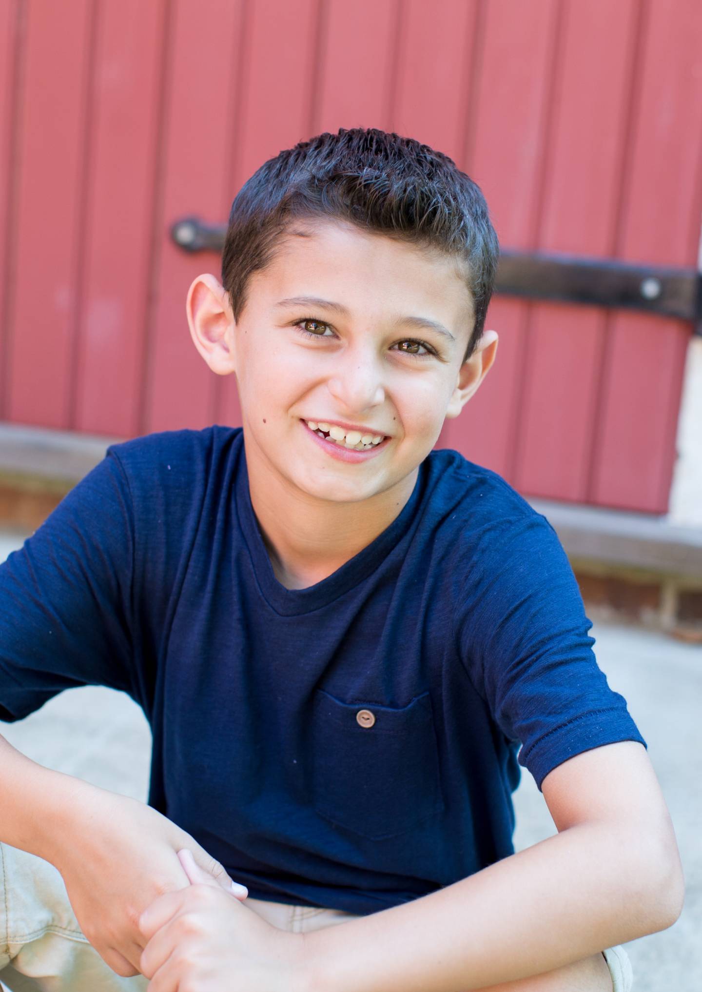 Young boy in a blue T-shirt smiling widely.