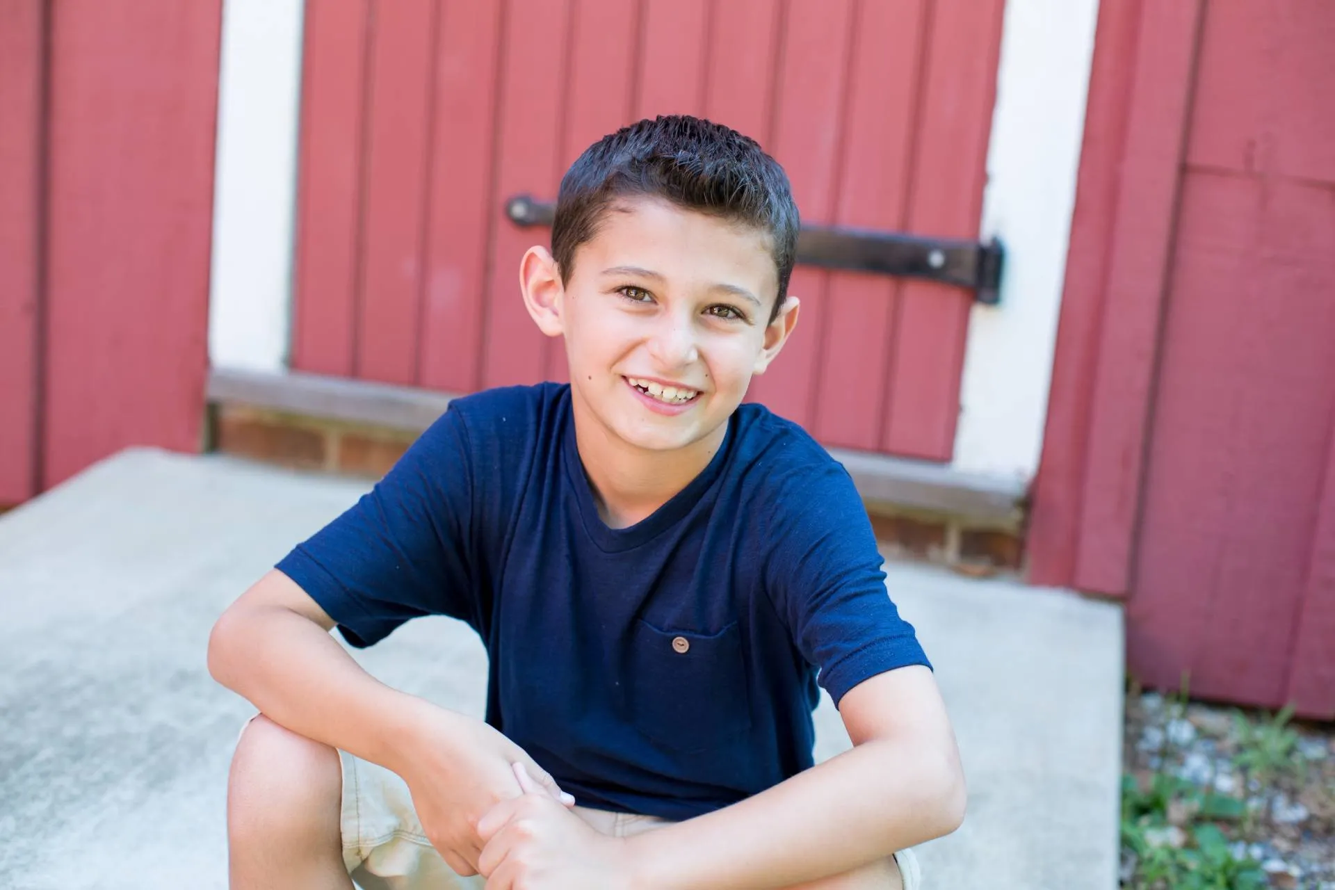 A young boy wearing a blue T-shirt smiling broadly.