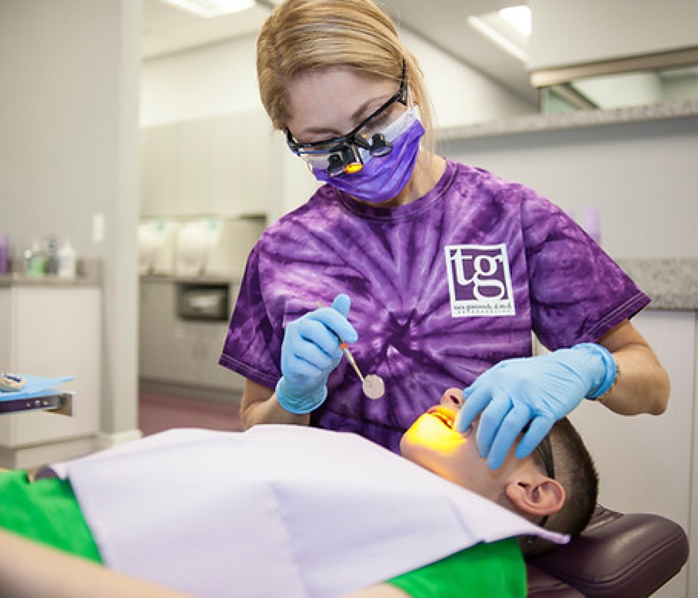 A dental tech working on a young boy in an exam chair at the orthodontic office.