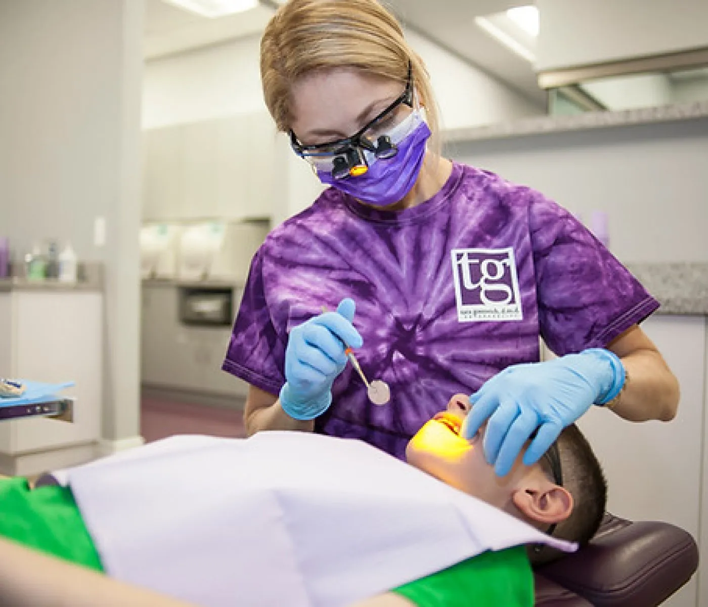 A dental tech working on a young boy in an exam chair at the orthodontic office.