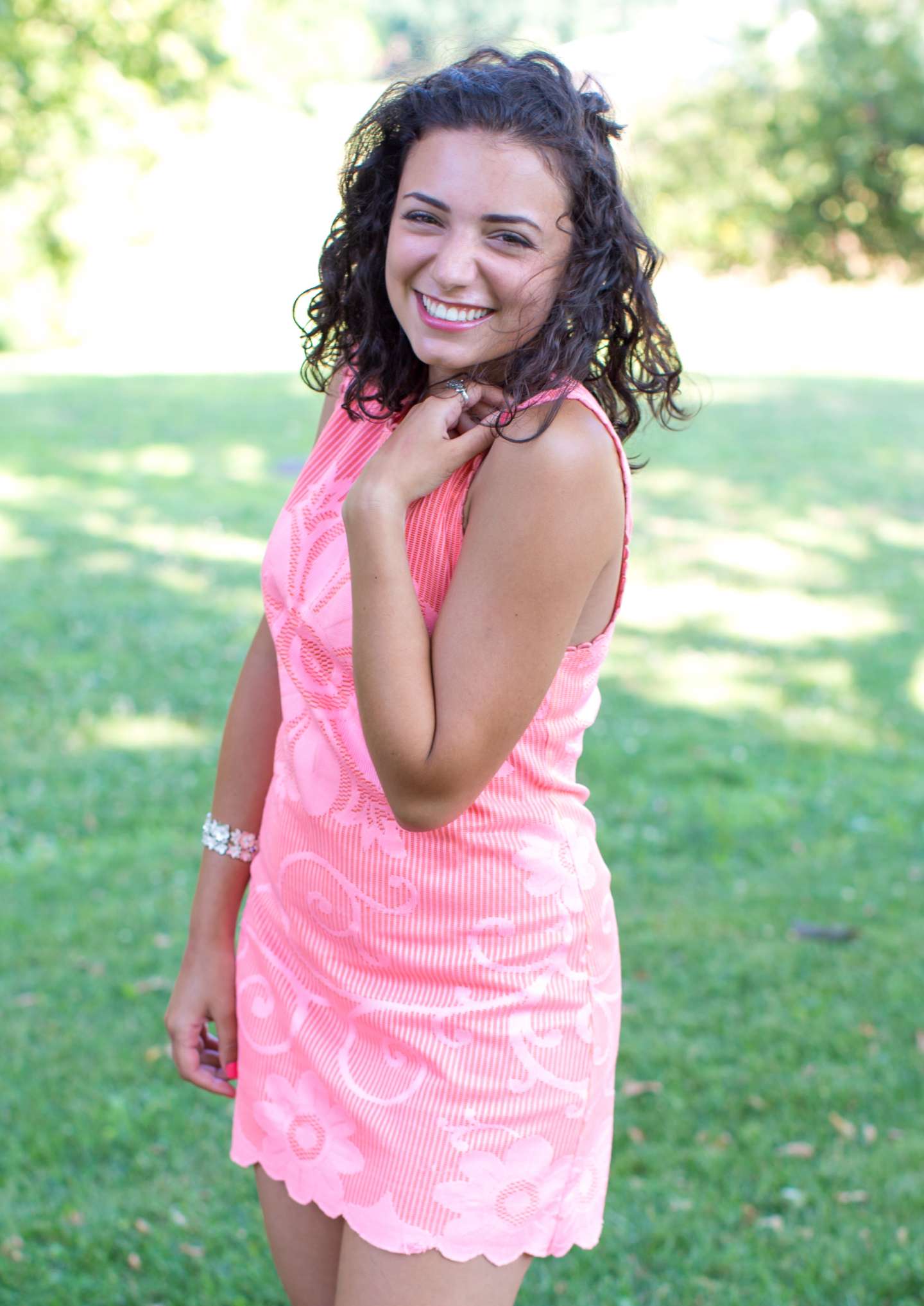 Young woman in a pink dress smiling brightly.