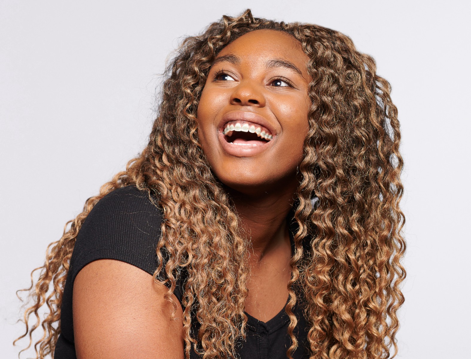 An African American woman with long curly hair, smiling broadly.