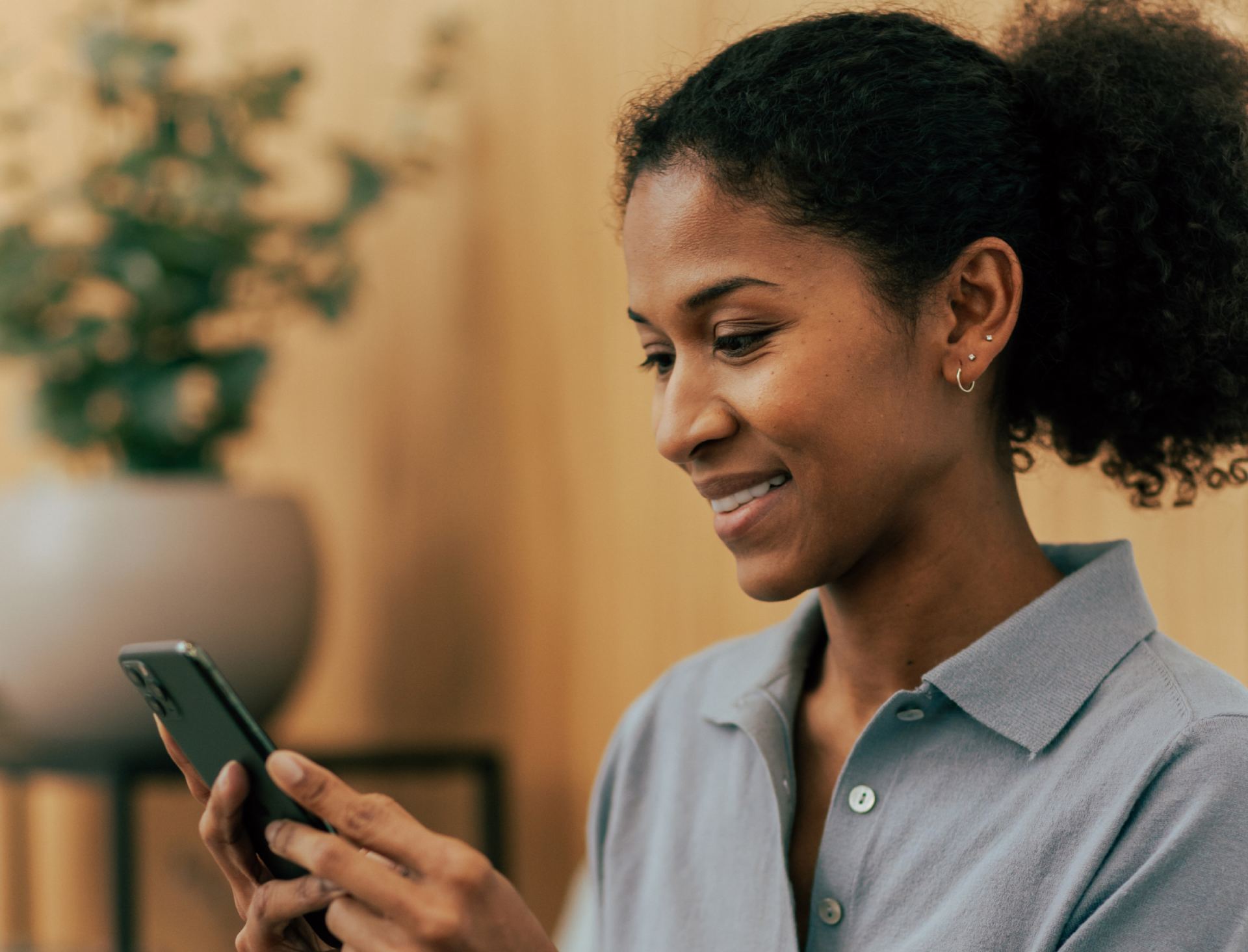 Smiling woman looking at her phone, relaxed after jaw Botox for tension and clenching